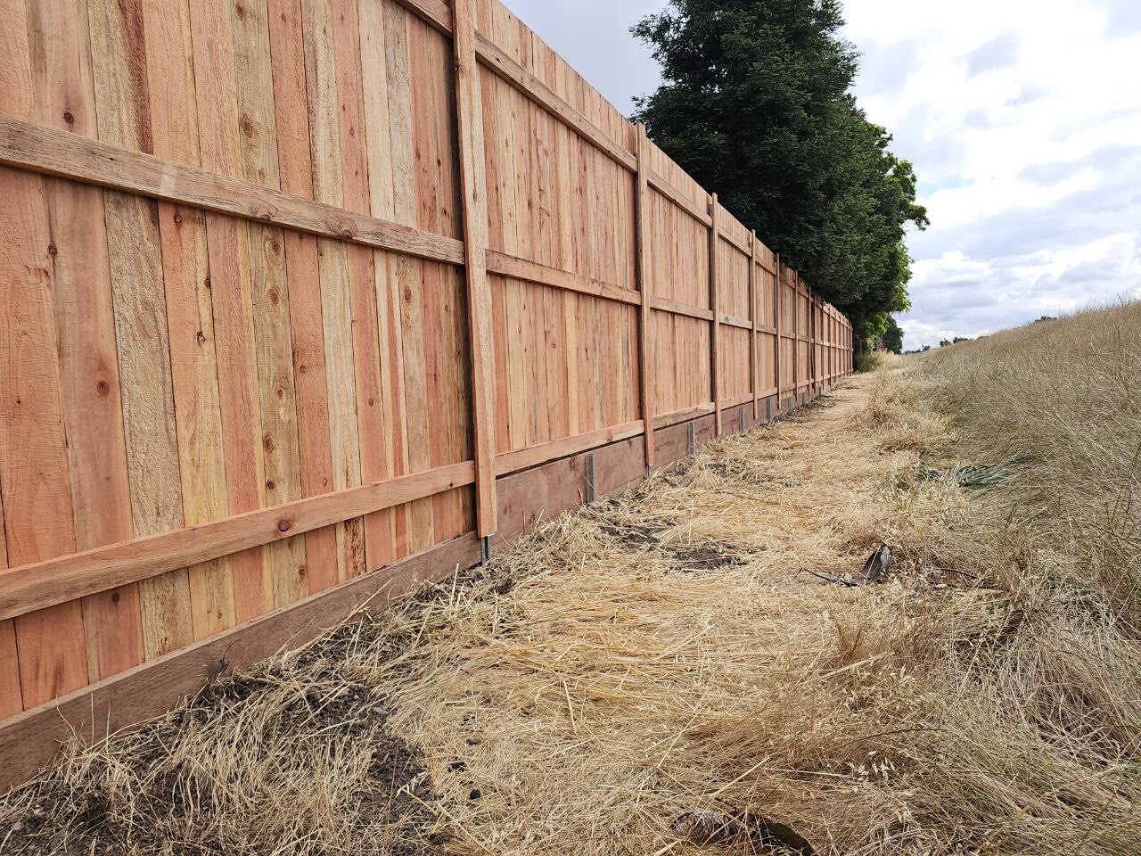 Long redwood fence along an open field